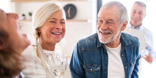 4 ældre mennesker interagerer smilende sammen i et køkken