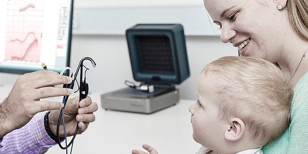 Et lille barn sidder hos sin mor, mens det får foretaget en REM måling af hørespecialist