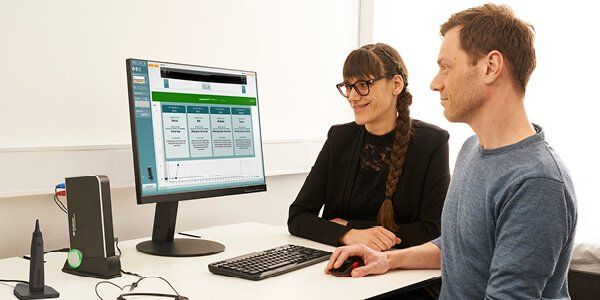 En hørespecialist viser sin patient resultaterne af patientens ACT test på sin computerskærm