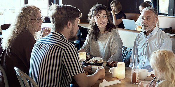 En gruppe mennesker sidder ved et bord og snakker sammen 